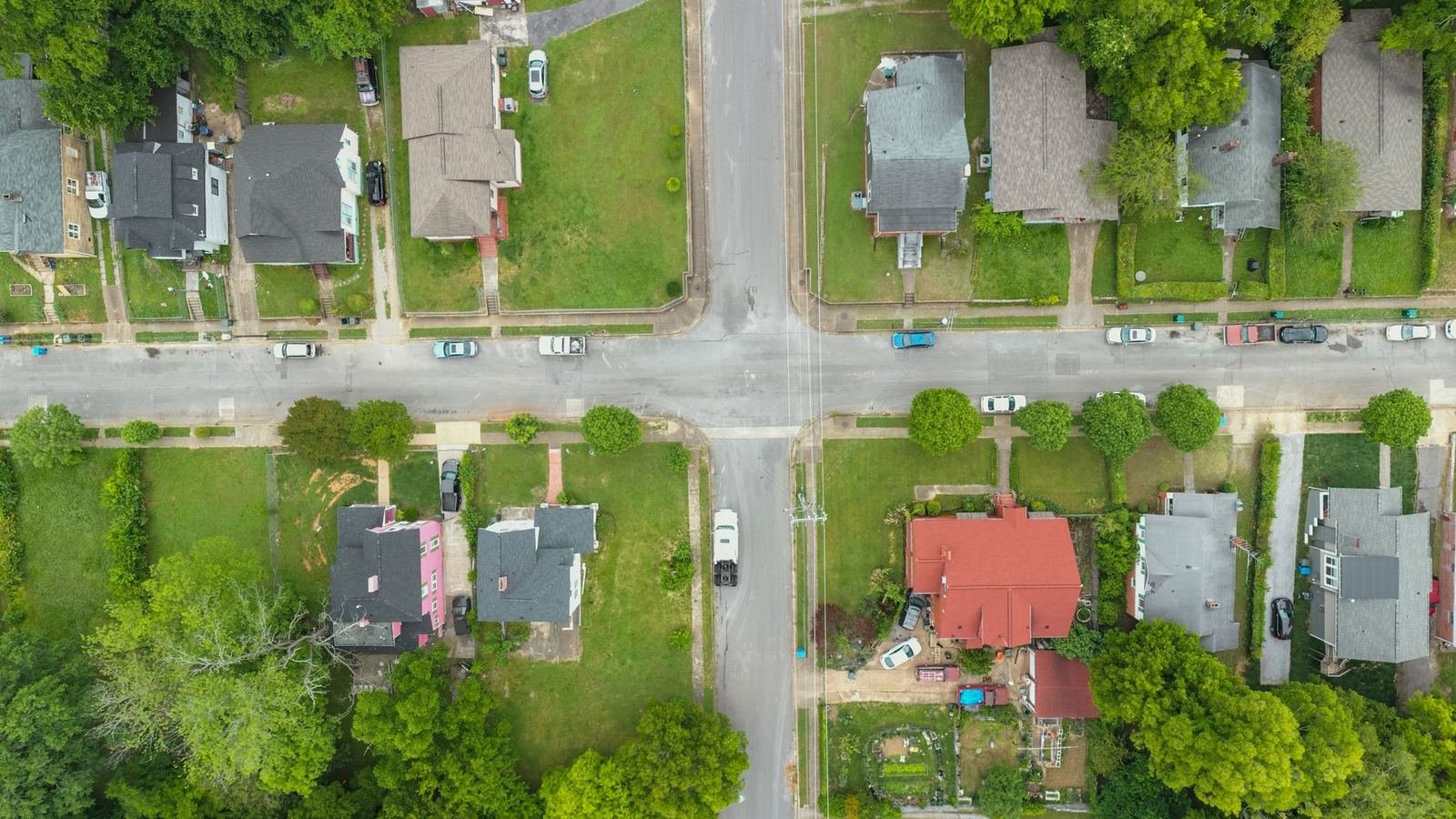 Aerial view of a suburban intersection with houses, yards and trees