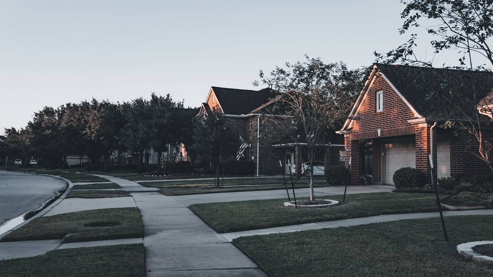 Brick houses with lawns and a curving sidewalk on a quiet suburban street