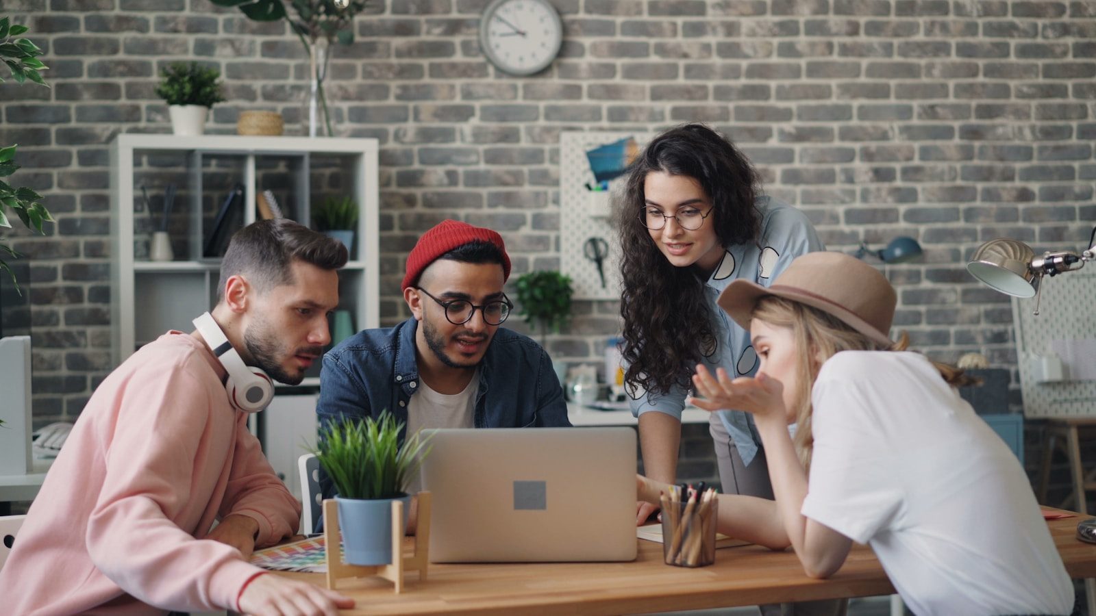 Four people gathered around one laptop at a table