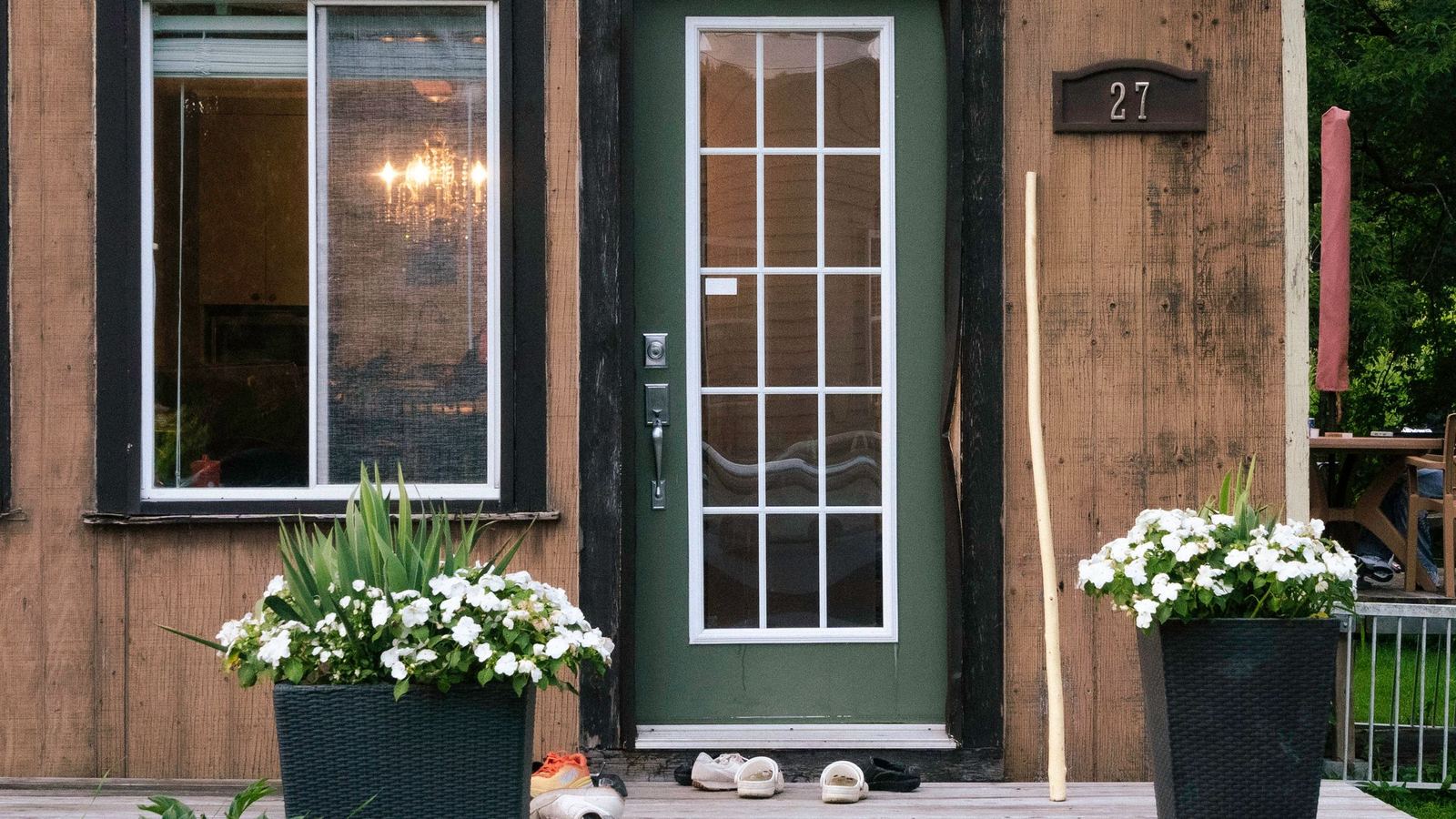 Front door of a wooden house with white flowers in planters on each side