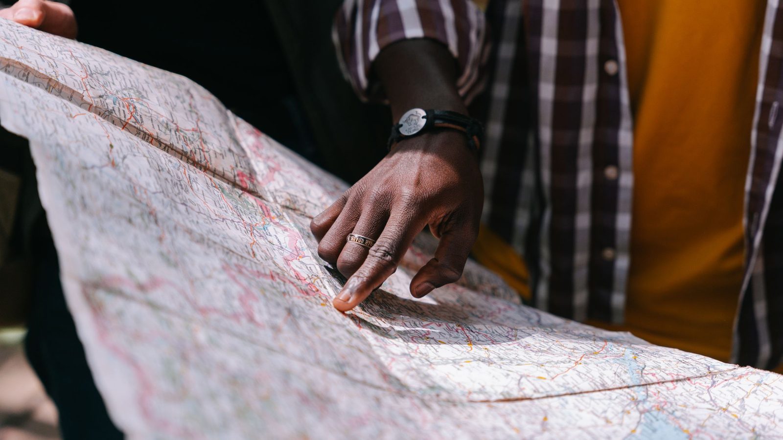 A hand points to a spot on a large unfolded paper map