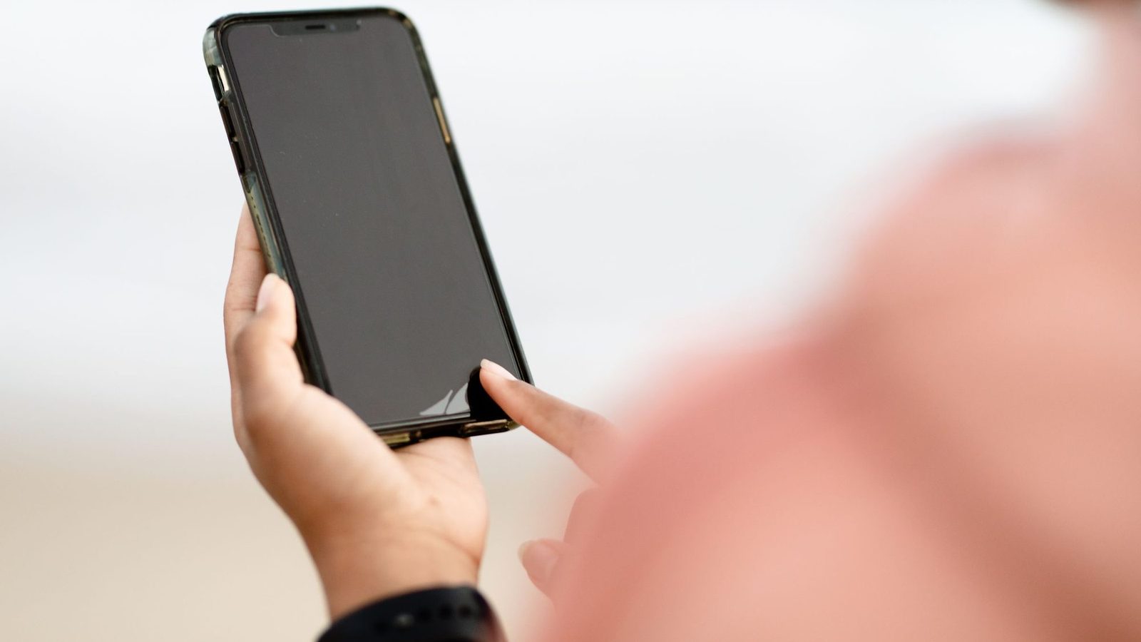 A hand holding a smartphone and tapping the screen