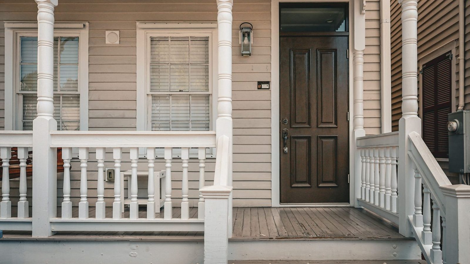 A white wooden front porch with turned posts and a dark front door