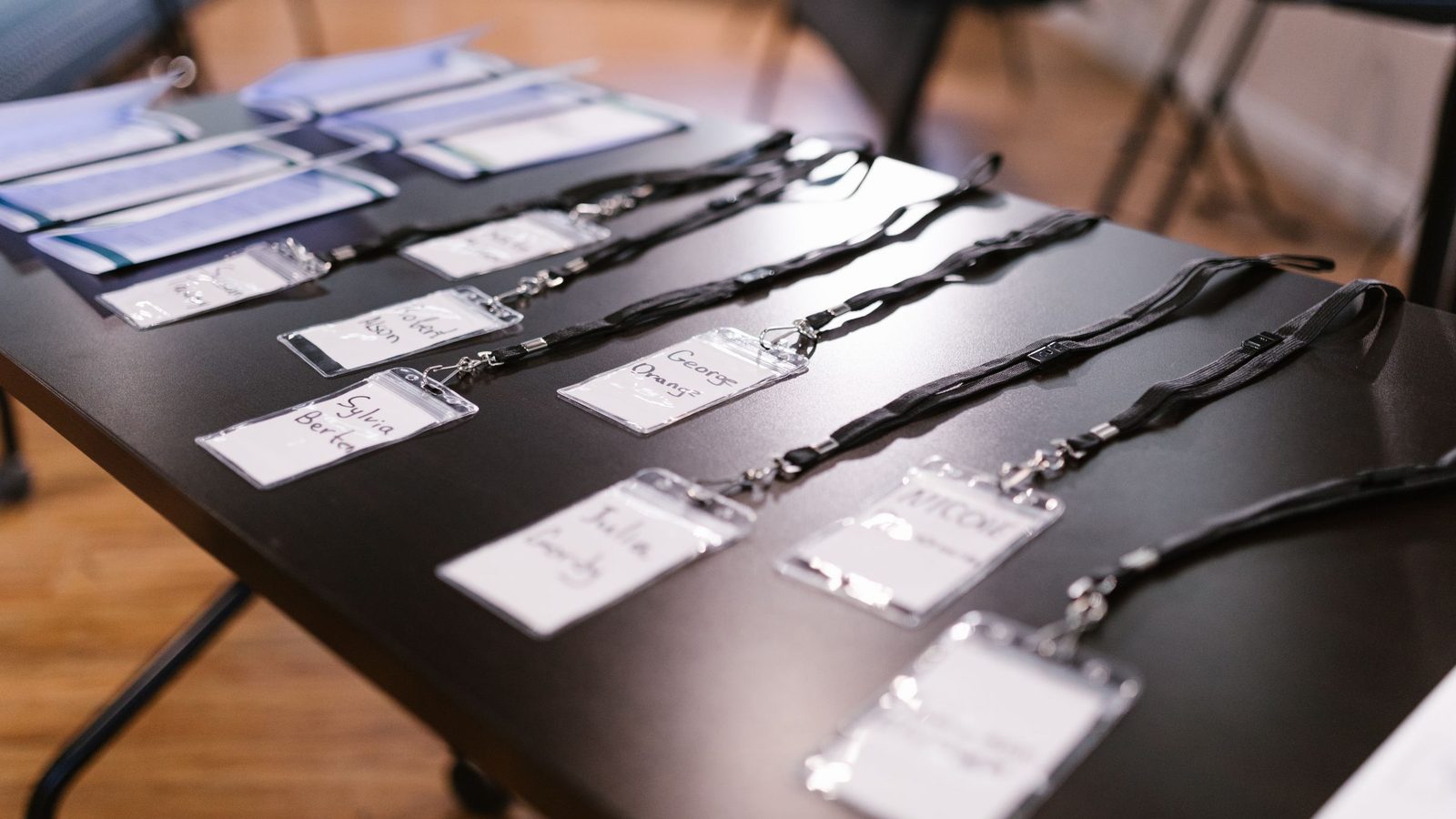 Name badges on black lanyards laid out in rows on a table