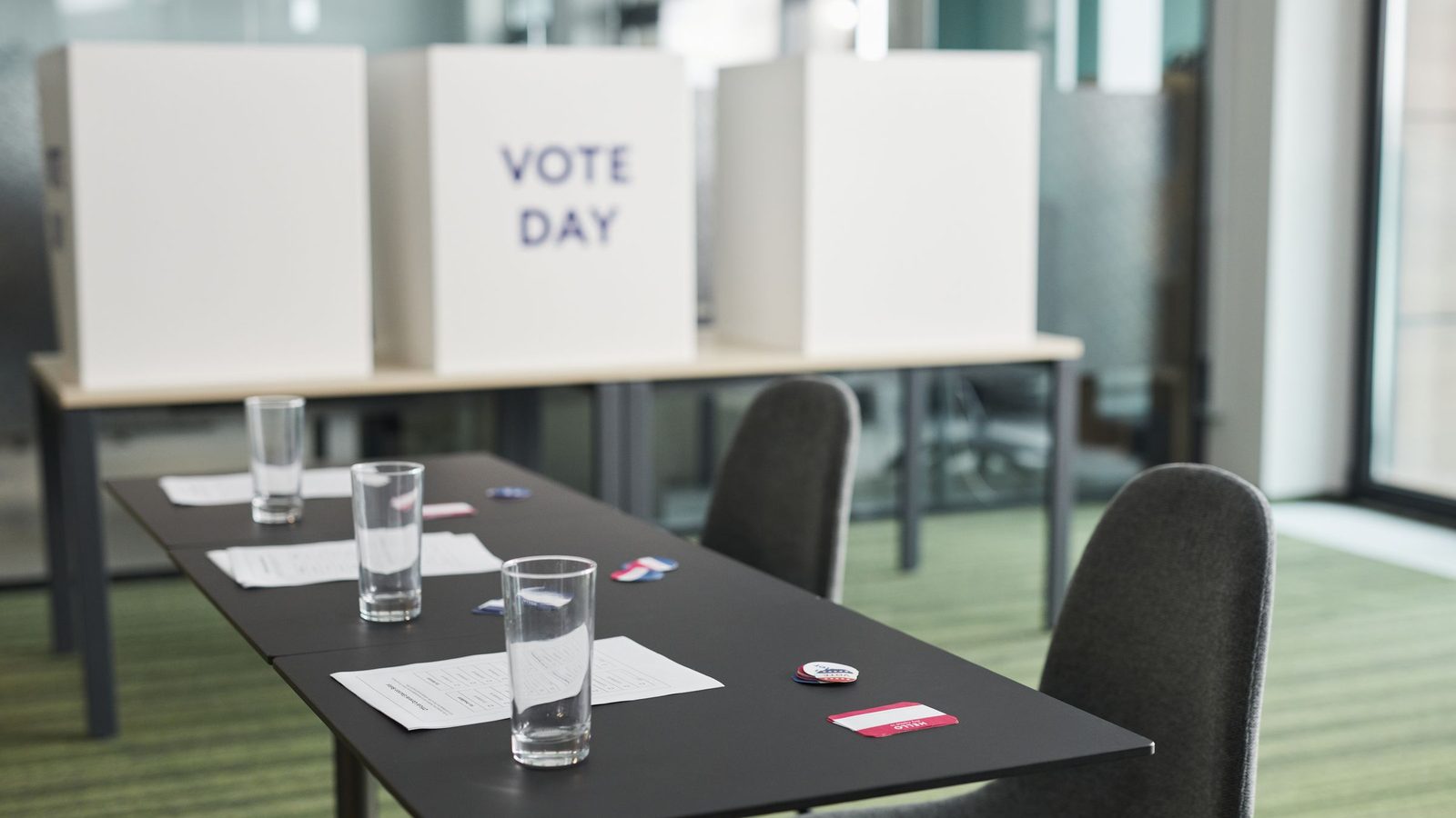 A polling place with white privacy booths marked Vote Day behind a table and chairs