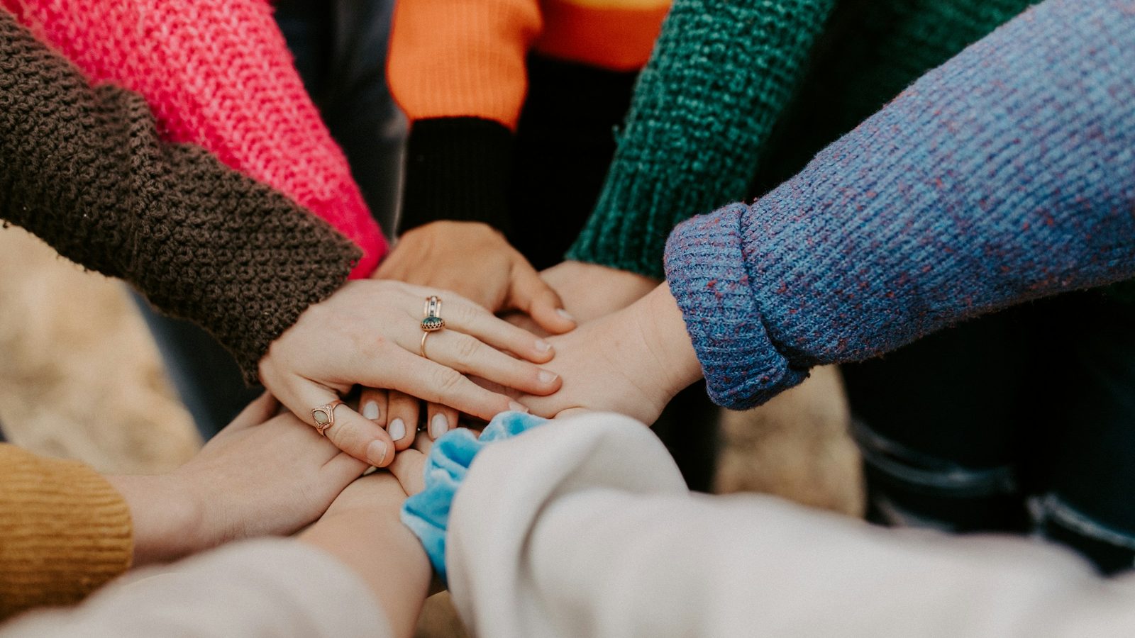 A group of people stack their hands together in a circle