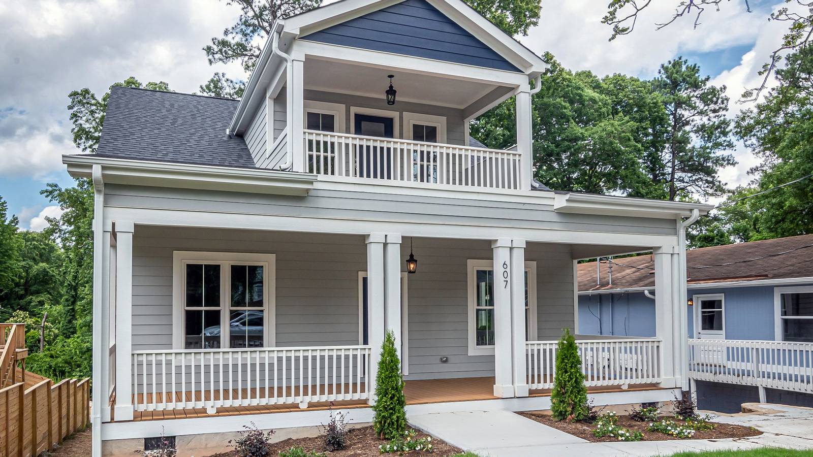 A white two-story house with a covered front porch and an upper balcony