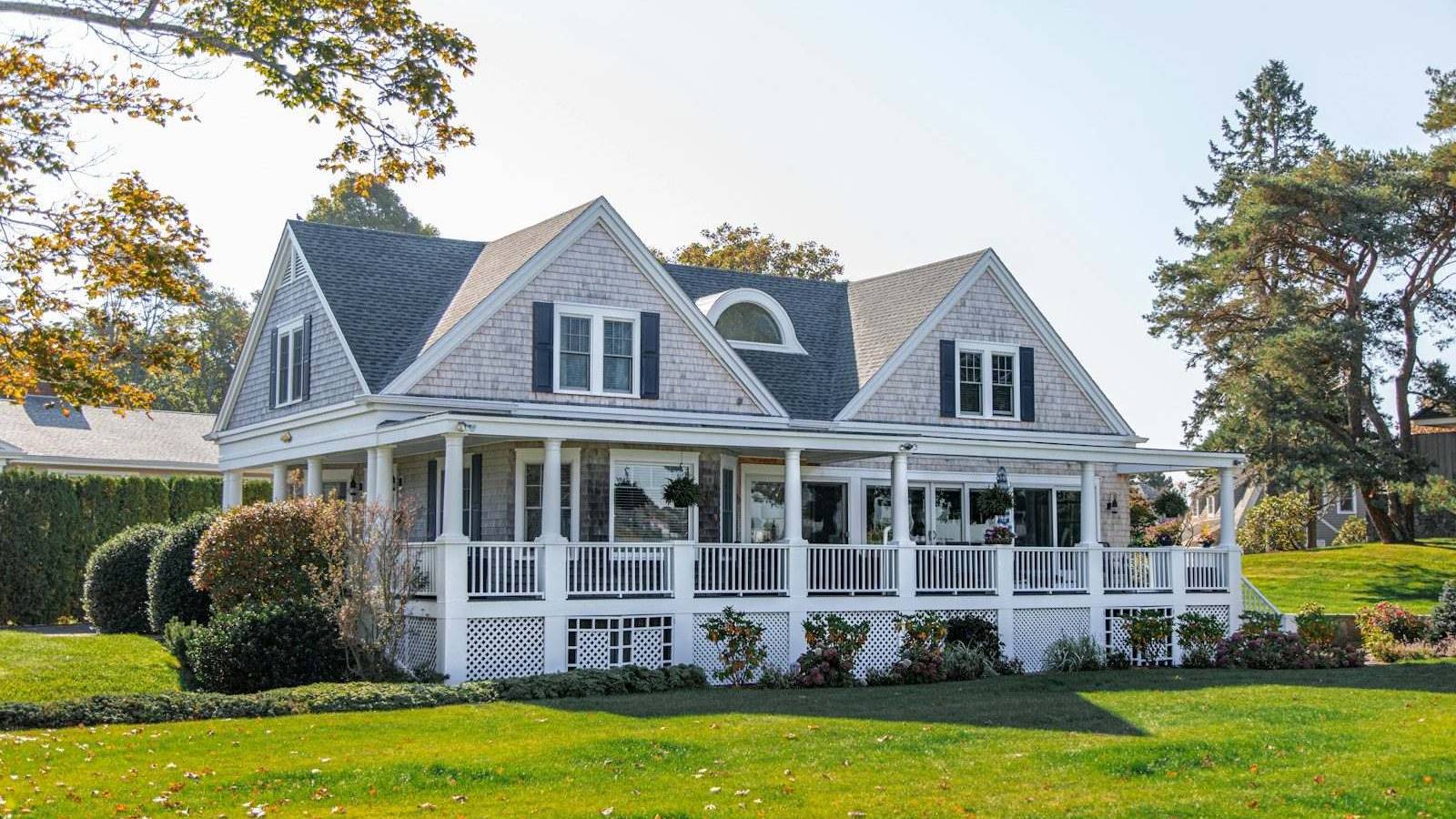 A large white house with a wraparound porch and a wide lawn